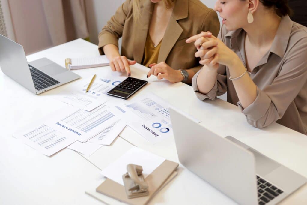 Accounting firm owner discussing client work at a desk in front of a laptop